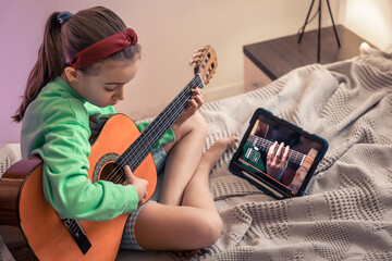 Little girl learns to play the guitar, online music video lesson.