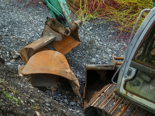 Fototapeta na wymiar Rusty metal excavator bucket different size on a ground by excavator. Heavy machinery equipment.