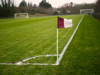 Fototapeta premium Purple and white corner flag on a football or soccer training ground. County Galway team colors, Ireland. Nobody. Selective focus