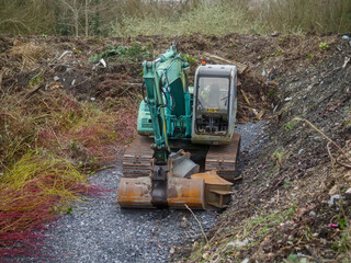 Old rusty and scratched excavator on a site in a forest or park. Heavy industry equipment with long usage life.