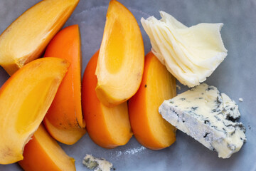 Sliced persimmon with pieces of blue cheese on a gray-blue plate