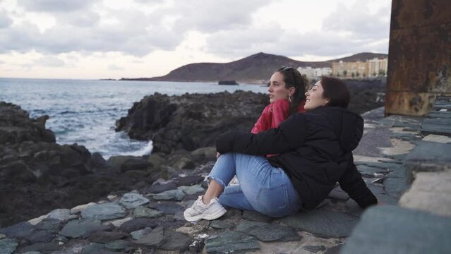 couple of two Caucasian lesbian women in love sitting chatting and enjoying themselves by the seaside