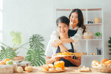 Young Asian couple doing holiday together in the kitchen happily wearing apron. love and valentine concept