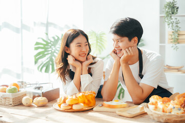 Young Asian couple doing holiday together in the kitchen happily wearing apron. love and valentine concept