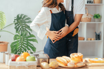 Young Asian couple doing holiday together in the kitchen happily wearing apron. love and valentine concept