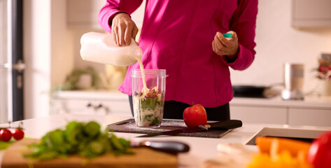 Close Up Of Woman In Kitchen Wearing Fitness Clothing Blending Fresh Ingredients For Healthy Drink