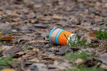 Old disposable coffee cup in the forest. Take away food industries impact on the...