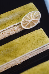 Three chocolate cakes on a black background. Mousse cake with lemon. Cake Opera for desserts on the menu, cakes on a black background. Selective focus