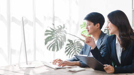 Two asia business person in formal suit working in office together , stock trader trading in computer together, bookkeepers working with online balance sheet, asset, profit or loss of limited company © M+Isolation+Photo