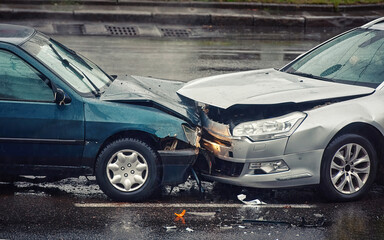 Car accident on wet road during rain, head on collision side view. Two cars damaged after head-on...