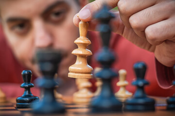 Hand of a man taking a chess piece to make the next move in a chess game. Close up. Spring day...