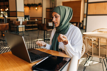 Muslim businesswoman having a video call in a cafe