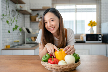 Pretty Asian woman preparing healthy breakfast at home in modern and beautiful kitchen, smiling brightly.