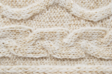 Beige soft woolen sweater surface with cable ornament texture and golden metallic fibres as background