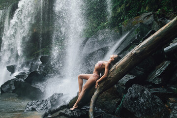 Gorgeous wet woman posing beside mighty Phnom Kulen waterfall