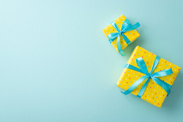 Easter decorations concept. Top view photo of vivid yellow gift boxes with blue ribbon bows on isolated pastel blue background with copyspace
