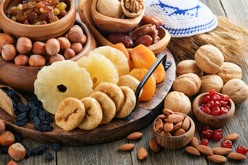 Tu Bishvat celebration concept. Mix of dry fruits and nuts almonds, hazelnuts, walnuts, apricots, prunes, cherries, raisins, dates, apples, figs over wooden table. Jewish holiday, new year of trees.