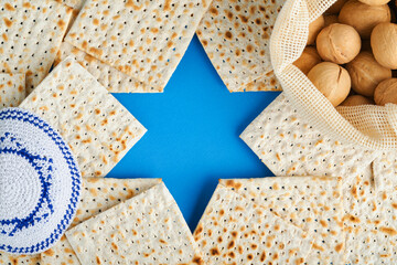 Passover celebration concept. Blue Star of David made from matzah, white and yellow roses, kippah...
