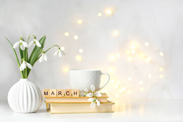 snowdrop flowers, cup, books and wooden letters 