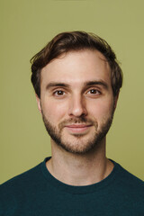 Fototapeta premium Young man smiling at camera while posing isolated over green background