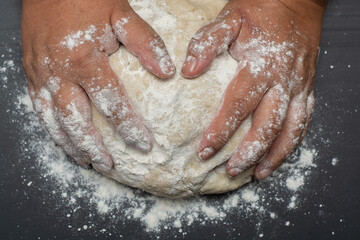 Fototapeta premium hands kneading bread dough on black table