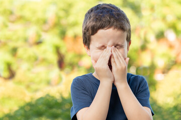 Child with allergy coughing in a green color field in summer