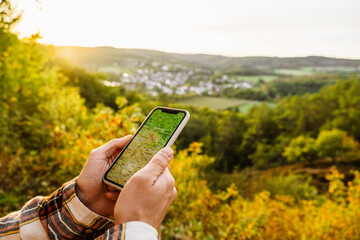 Close up of man hands using navigation app on mobile phone during hiking