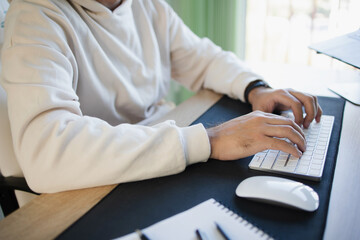 Close-up of a man programmer typing on the keyboard sitting in the office desk. Hands of young contemporary office manager over laptop keypad during work 