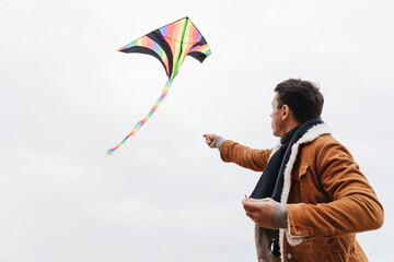 Man playing with flying kite outdoors