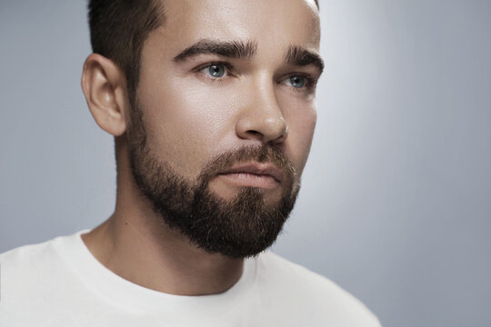 Young and handsome bearded  man with clean skin against gray background