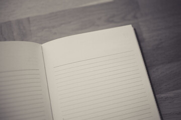 Blurred image of open notebook on wooden table, vintage filter with space for text
