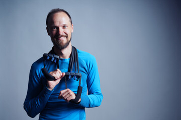 Mid age slim smiling man with sport rubber expander over shoulders