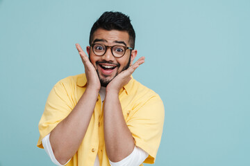 Smiling bearded indian guy gesturing while posing isolated over blue wall