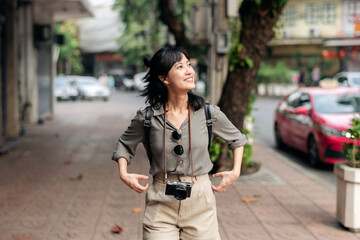 Young Asian woman backpack traveler enjoying street cultural local place and smile. Traveler checking out side streets. Journey trip lifestyle, world travel explorer or Asia summer tourism concept