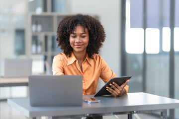 Using laptop computer, Young pretty african american business woman bookkeepers working with...
