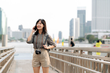 Fototapeta na wymiar Young Asian woman backpack traveler using mobile phone in express boat pier on Chao Phraya River in Bangkok. Journey trip lifestyle, world travel explorer or Asia summer tourism concept