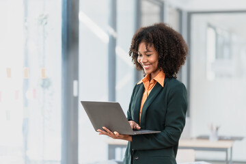 Using laptop computer, Young pretty african american business woman bookkeepers working with...