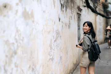 Obraz na płótnie Canvas Young Asian woman backpack traveler using digital compact camera, enjoying street cultural local place and smile. Traveler checking out side streets. Journey trip lifestyle