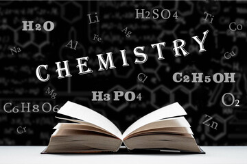The study of the chemistry, composition and structure of matter. An open book, a textbook lies on the table. Chemical formulas and signs of chemical elements on a black background.