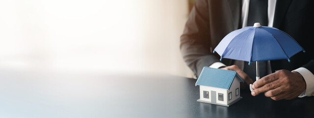 Individuals holding small umbrellas and model homes, housing insurance against impending loss and fire, building fire insurance, home and real estate insurance concepts.