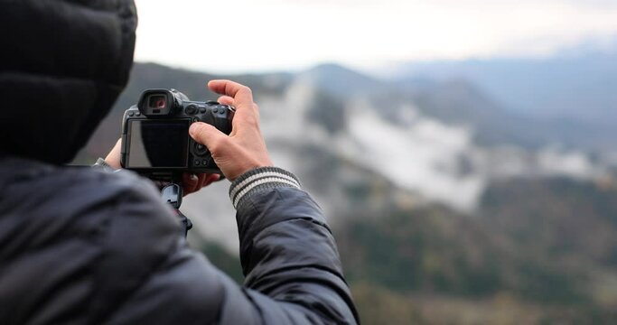Photographer at work in mountains photographs panorama of nature