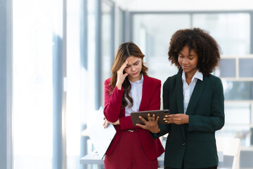 Fototapeta premium Young trader mixed race woman in formal suit friends consulting and discussing with stock market and cryptocurrency in online trading application. Fails, unhappy, bad day