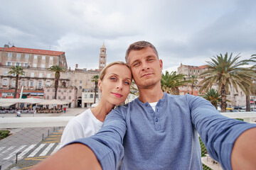 Travel by Croatia. Pretty young loving couple taking selfie together in Split old town.