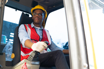 Male construction worker operating on Skid tractor or construction vehicle at building site.