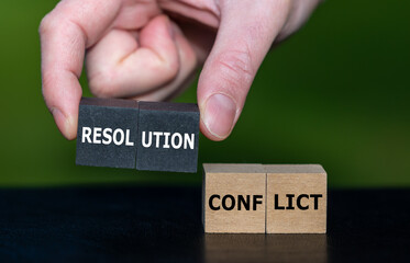 Hand picks wooden cubes with the expression 'resolution' instead of cubes with the word 'conflict'. Symbol for solving a conflict.
