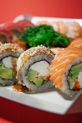 salmon tuna chuka shrimp eel nigiri gunkan sushi rolls set in white box on red background
