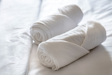 Fototapeta na wymiar Soft pillows and white towel on clean white bed. Pillows bed with bedding sheets in bedroom. Bed sheets and pillows messed. Hotel, resort or home can relax on bed for deep sleep.