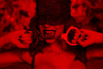Sexy woman bite handcuffs in lace eye cover and red light