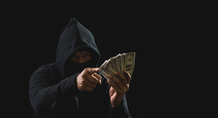 Hacker spy man hands wearing a black shirt, sitting on a chair and a table, is a thief, holding...