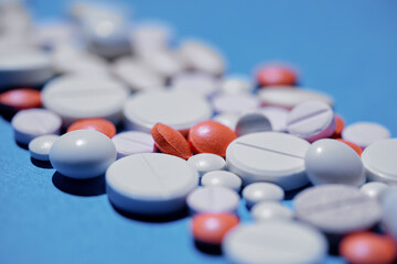 Medicine and drug concept. Pharmacy and health care. Close up shot of different pills and tablets in the middle of blue background.